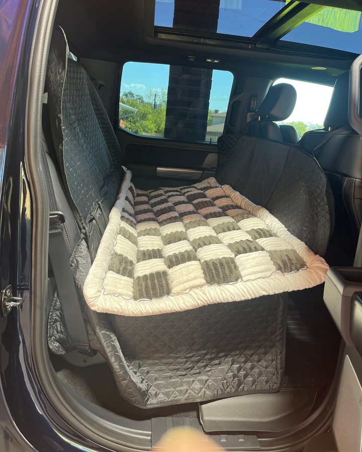 Gray Team K9 plush bed lying on the flat floor of a hard bottom seat cover in a truck