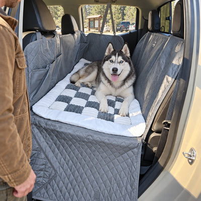 Siberian Husky lying on the plush bed on the gray seat cover in a pickup