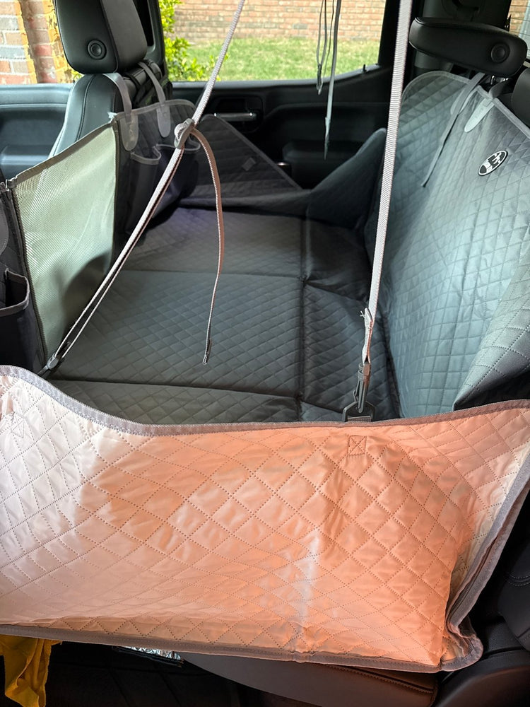 A Team K9 hard bottom seat cover installed in a crew cab truck, with a pink blanket on the floor panel