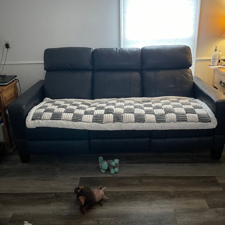 A customer's Gray Team K9 couch cover laid on the seat of a navy sofa